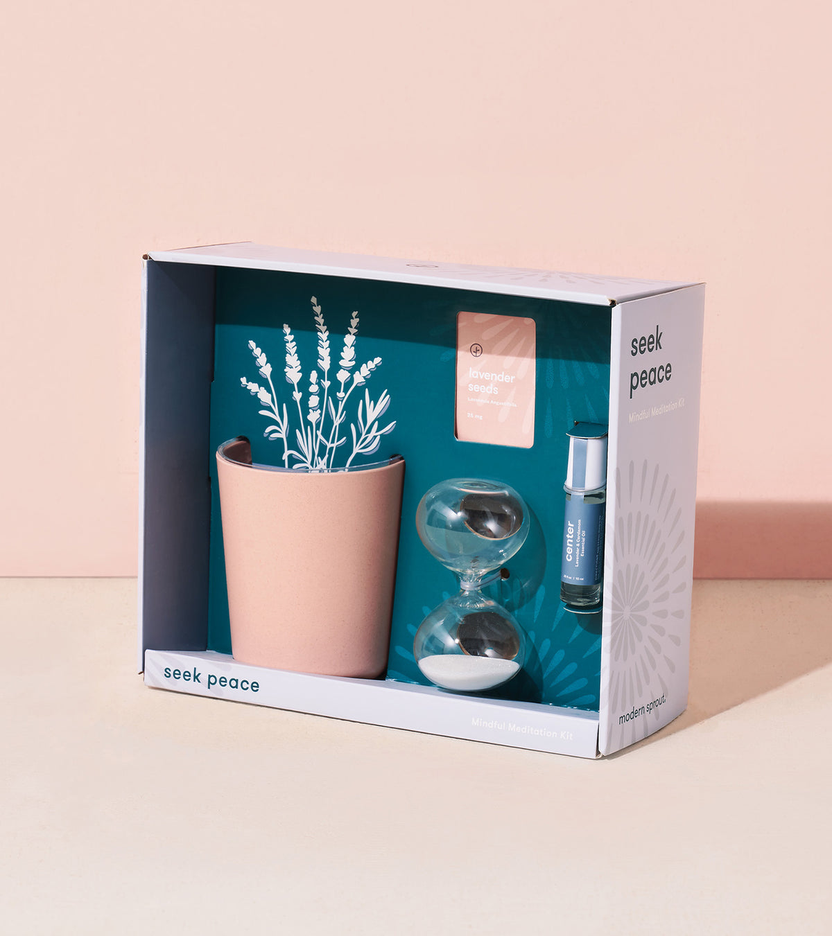 Mindful meditation kit featuring a pink planter with faux lavender, an hourglass, a calming essential oil, and a guided meditation card.