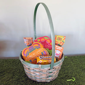 A woven Easter basket filled with colorful treats, including garden-themed items and cheerful snacks, set on green grass.