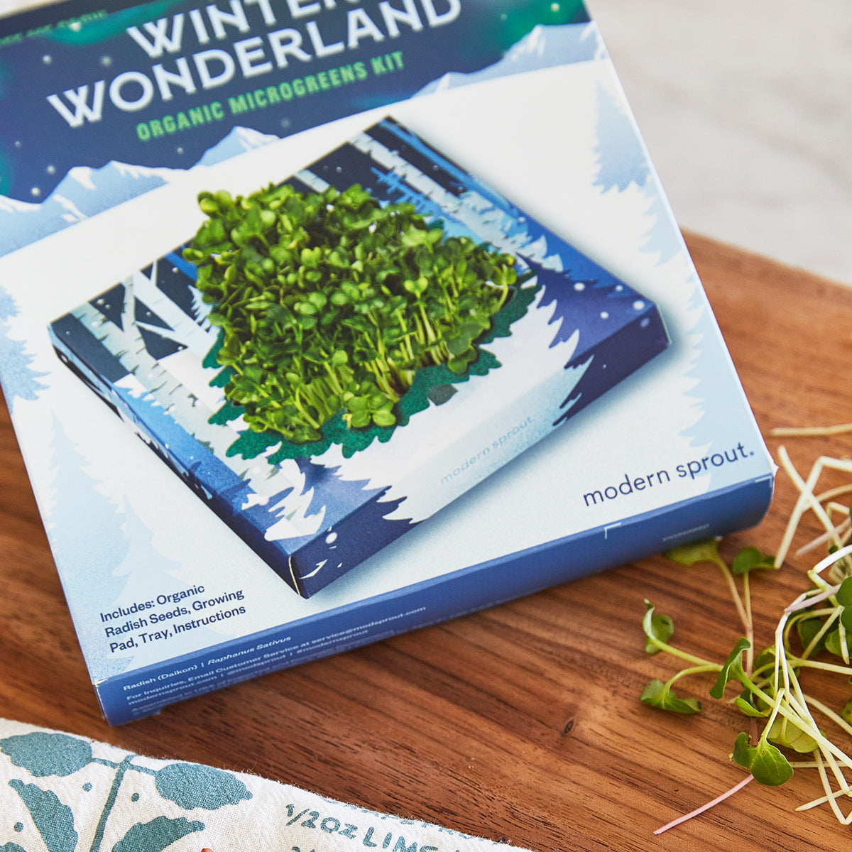 "Winter Wonderland organic microgreens kit with vibrant green sprouts on a snowy backdrop. Includes seeds, tray, and instr...