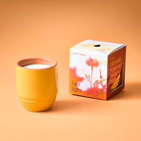 Yellow ceramic planter with a candle inside, accompanied by a colorful box labeled "Last Light" featuring floral imagery.