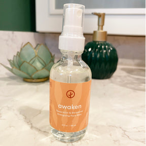 Three bottles of Shine Bright Face Mist featuring a refreshing spearmint and bergamot scent, displayed on a marble countertop.