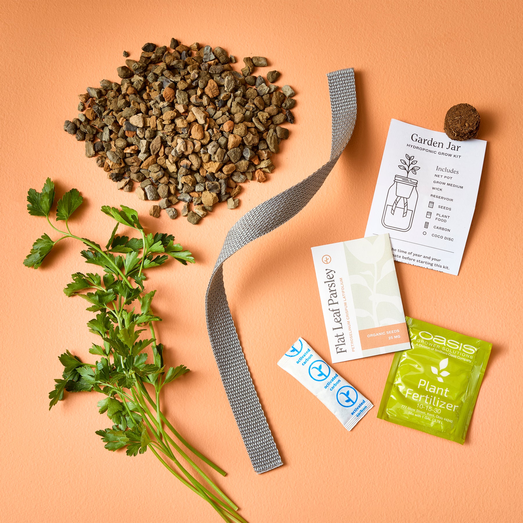 Passive Hydroponic Replant Kit components including gravel, plant fertilizer, seeds, and a growing guide on an orange background.