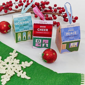 Colorful Home Grown Ornaments featuring herb grow kits for basil, peppermint, and lavender, arranged with festive decorations.