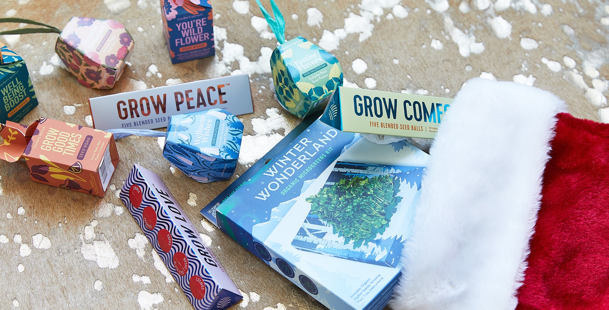 Colorful seed packets and a hydroponic kit displayed on textured surface, with a festive Santa hat nearby.