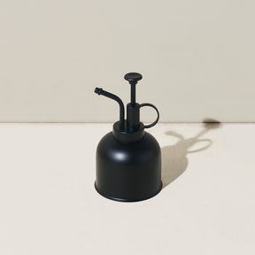 Black metal watering can with a long spout and a pump handle, designed for precise plant care.