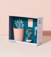 Mindful meditation kit featuring a pink planter with faux lavender, an hourglass, a calming essential oil, and a guided meditation card.