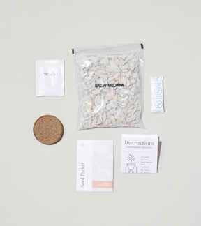Glow & Grow Kits components including seed packet, grow medium, cork disc, and instruction card arranged on a neutral background.