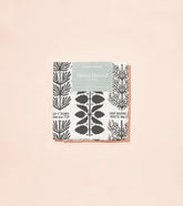 Herbal Harvest tea towel featuring botanical illustrations in black and white with a peach border, packaged attractively.