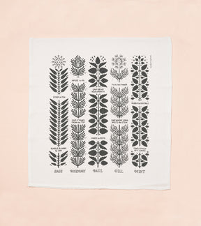 Tea towel featuring botanical illustrations of herbs including sage, rosemary, basil, dill, and mint, with labels.
